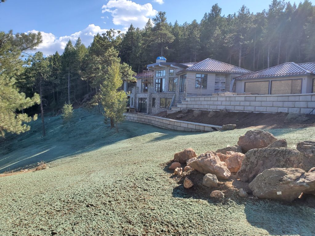 A large hillside behind a large and beautiful new build home with recent hydroseed / hydromulch for erosion control.