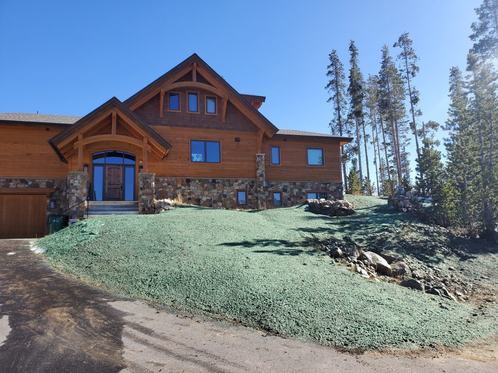 A residential yard in front of a large house with newly applied hydroseed / hydromulch for a new lawn and erosion control.