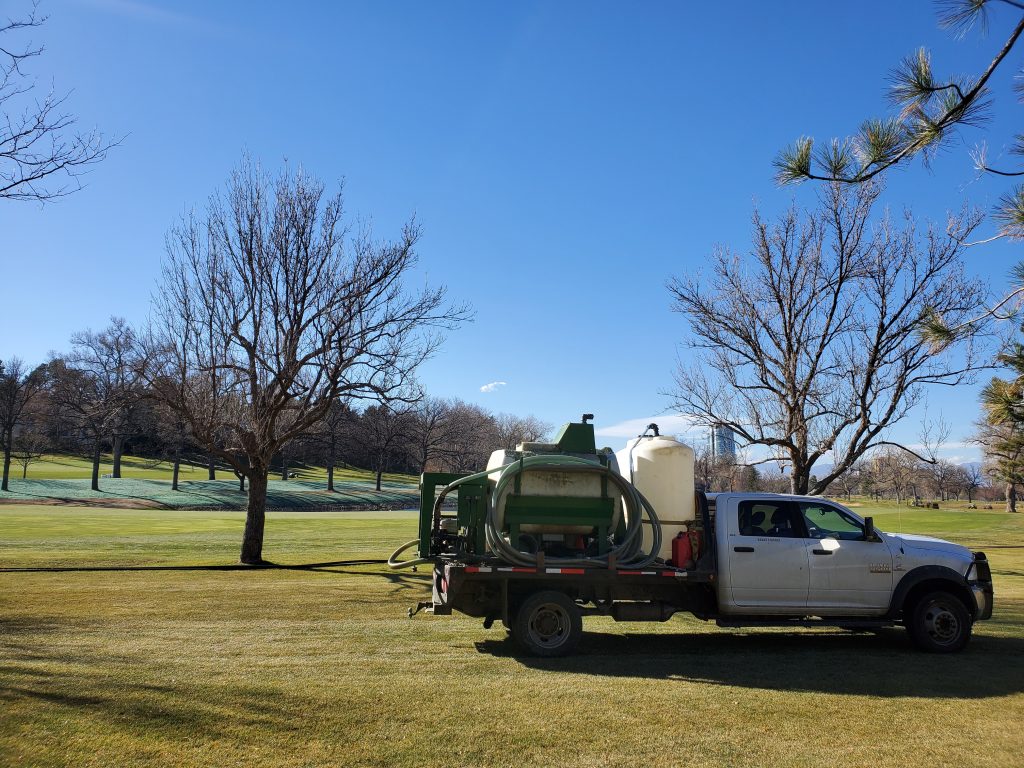A Foothills Hydroseed truck with hydroseeding equipement with a fresh area of recent hydroturfing in the background.